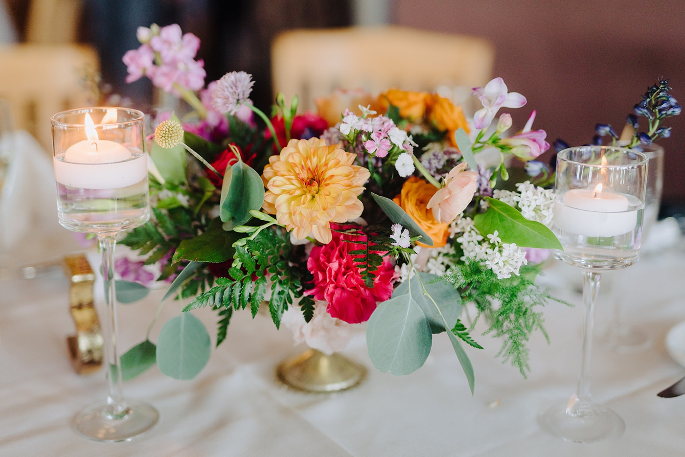 Floating candles and purple, pink, and orange floral centerpieces for a spring wedding reception
