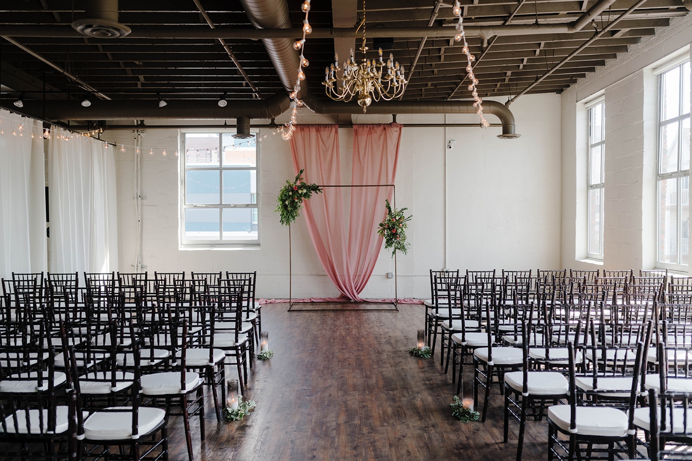 Industrial ceremony arch decorated with roses and pink drapery