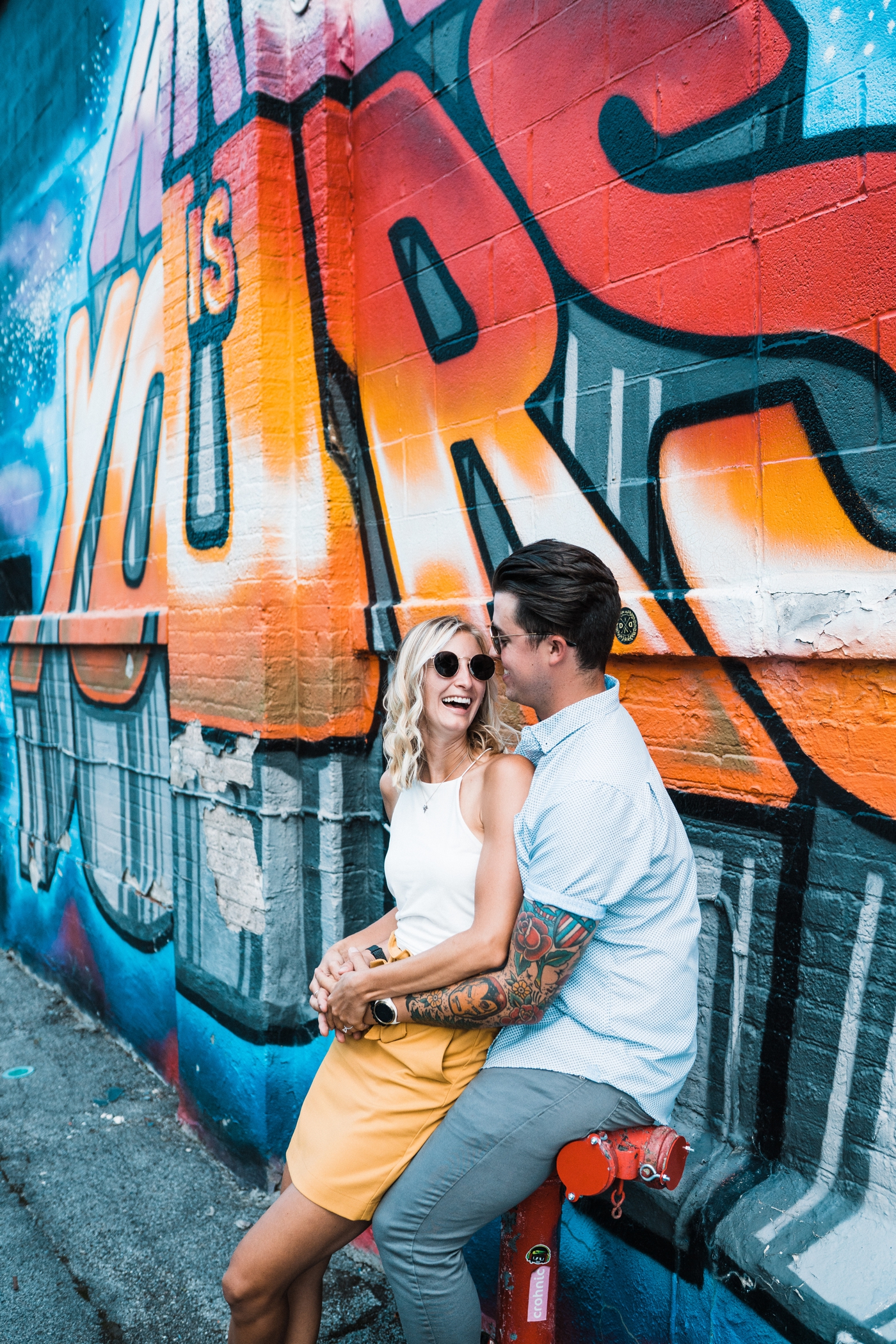 Bride and groom posing in front of street art for their engagement session