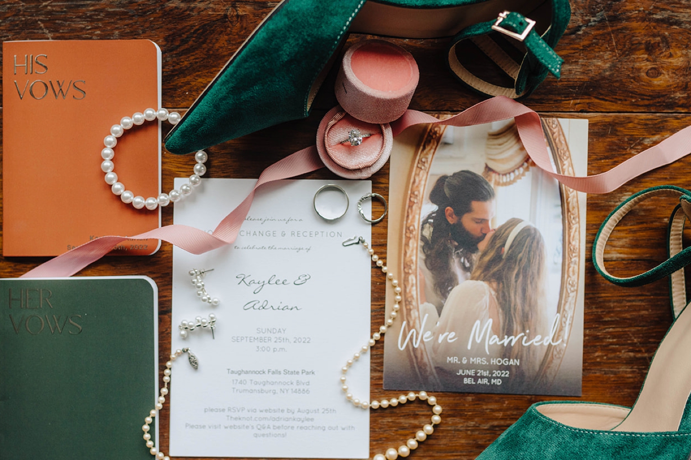 Flat lay of an invitation, vow books, and pearl jewelry for a wedding at Taughanock Falls