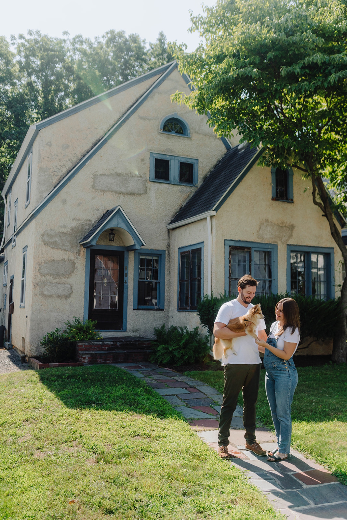 Couple posing in front of their home with their dog during their maternity session